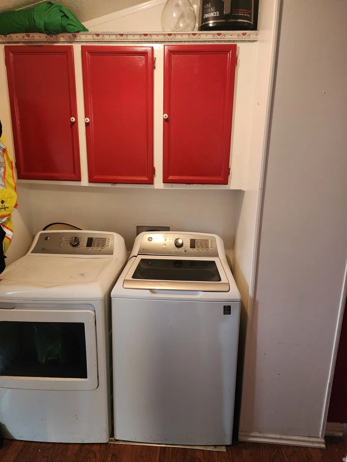 Laundry room featuring washing machine and dryer, cabinet space, and dark wood-style floors