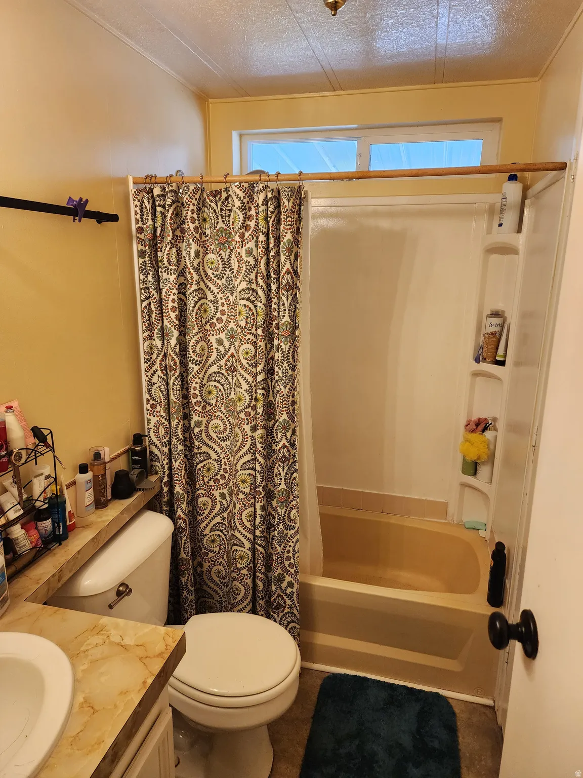 Bathroom with vanity, shower / bathtub combination with curtain, a textured ceiling, and plenty of natural light