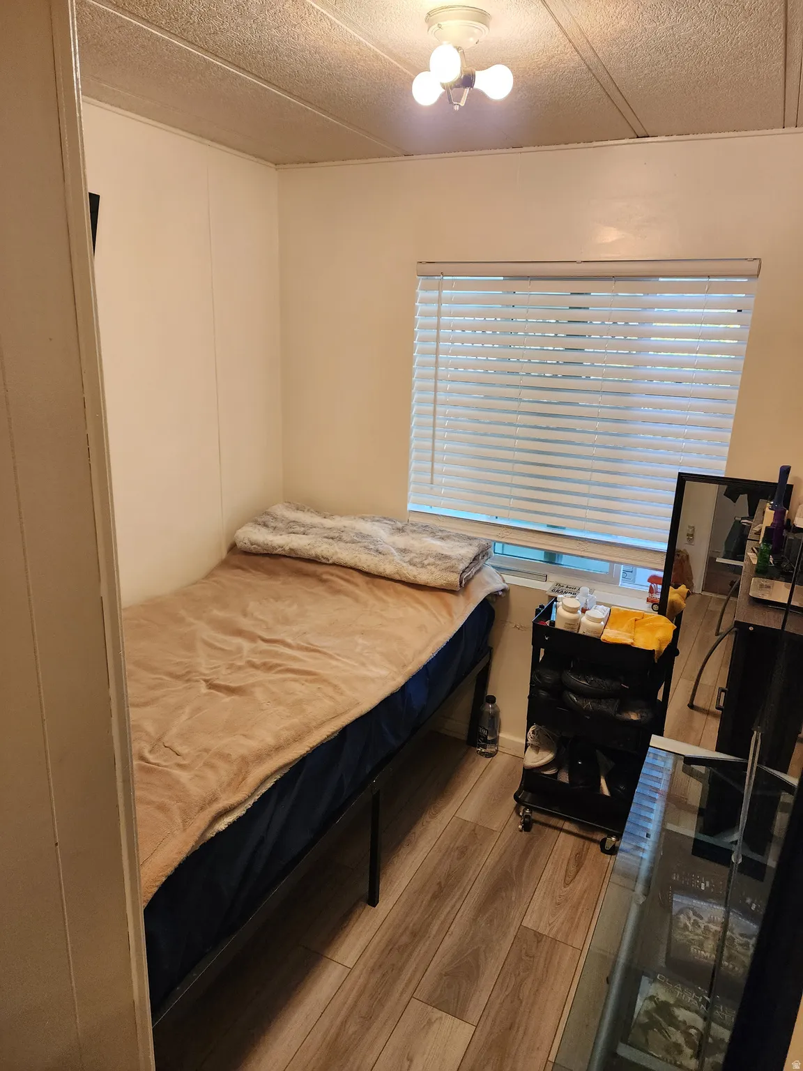Bedroom with a textured ceiling, light wood-style floors, and ceiling fan