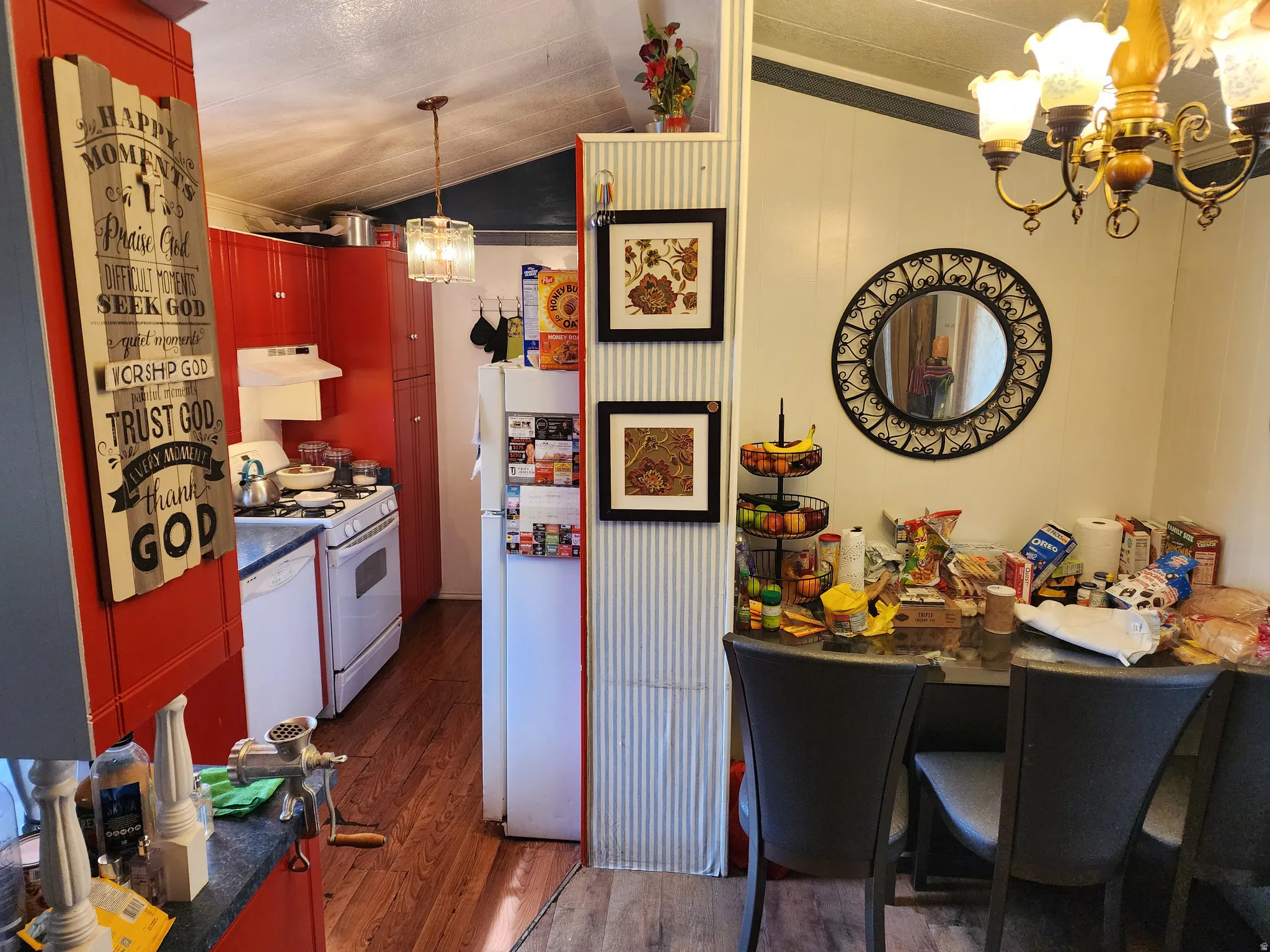 Kitchen featuring suspended lighting, dark wood-style flooring, white appliances, and dark countertops