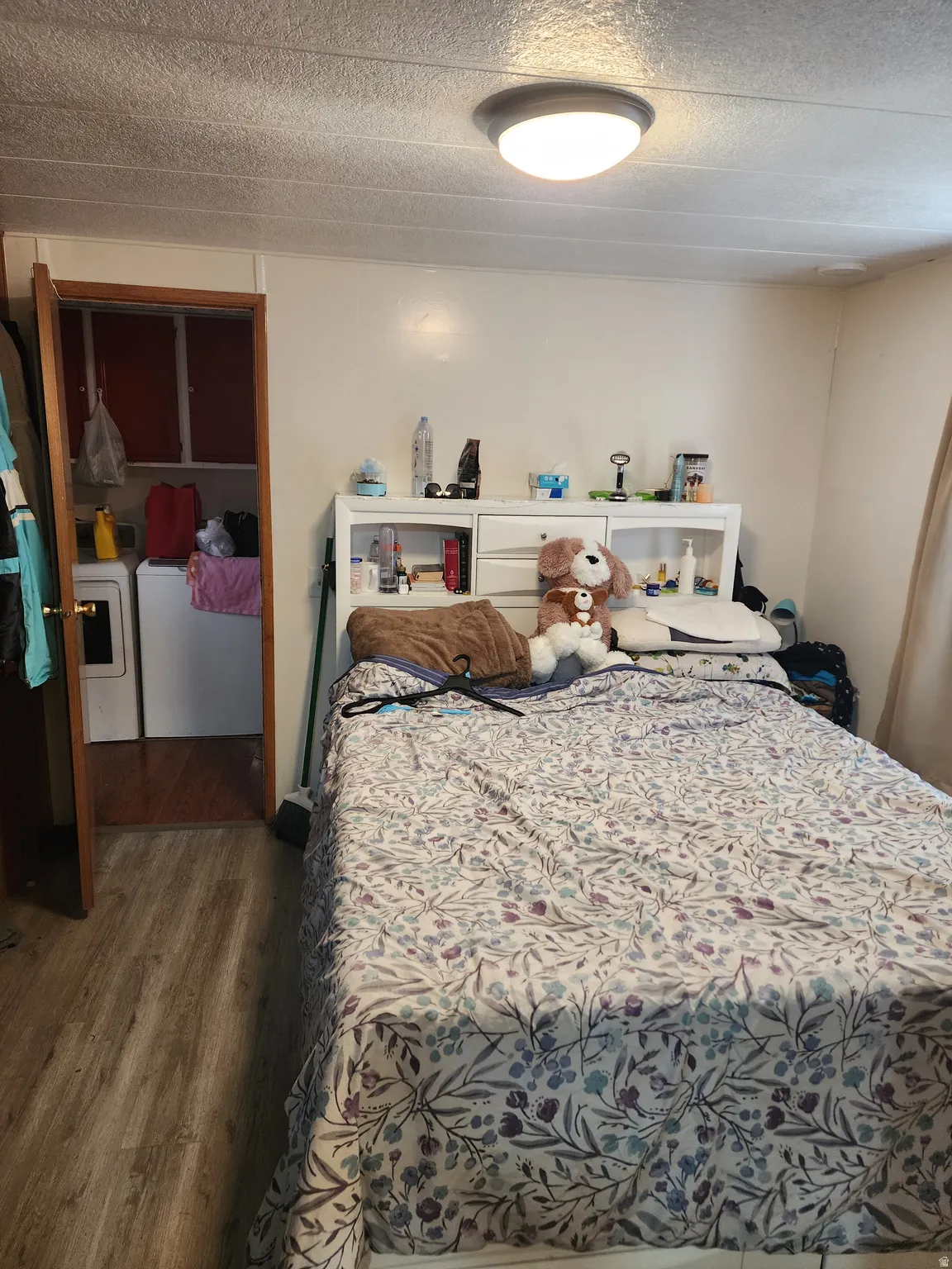 Bedroom featuring dark wood finished floors, washer / dryer, and a textured ceiling