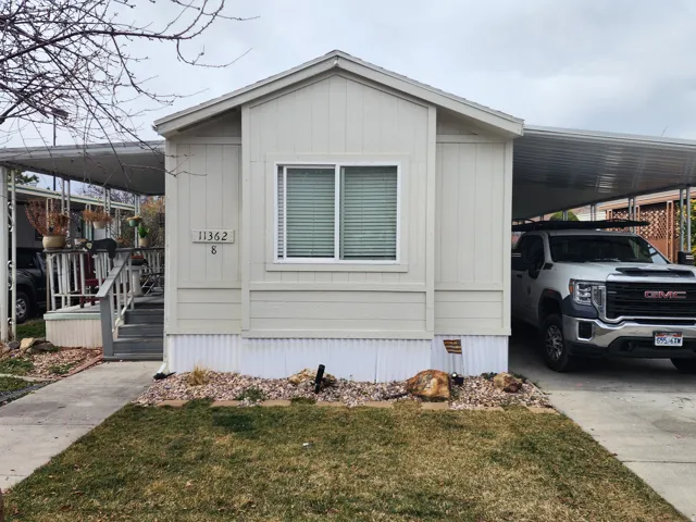 Manufactured / mobile home with an attached carport, a front lawn, and concrete driveway