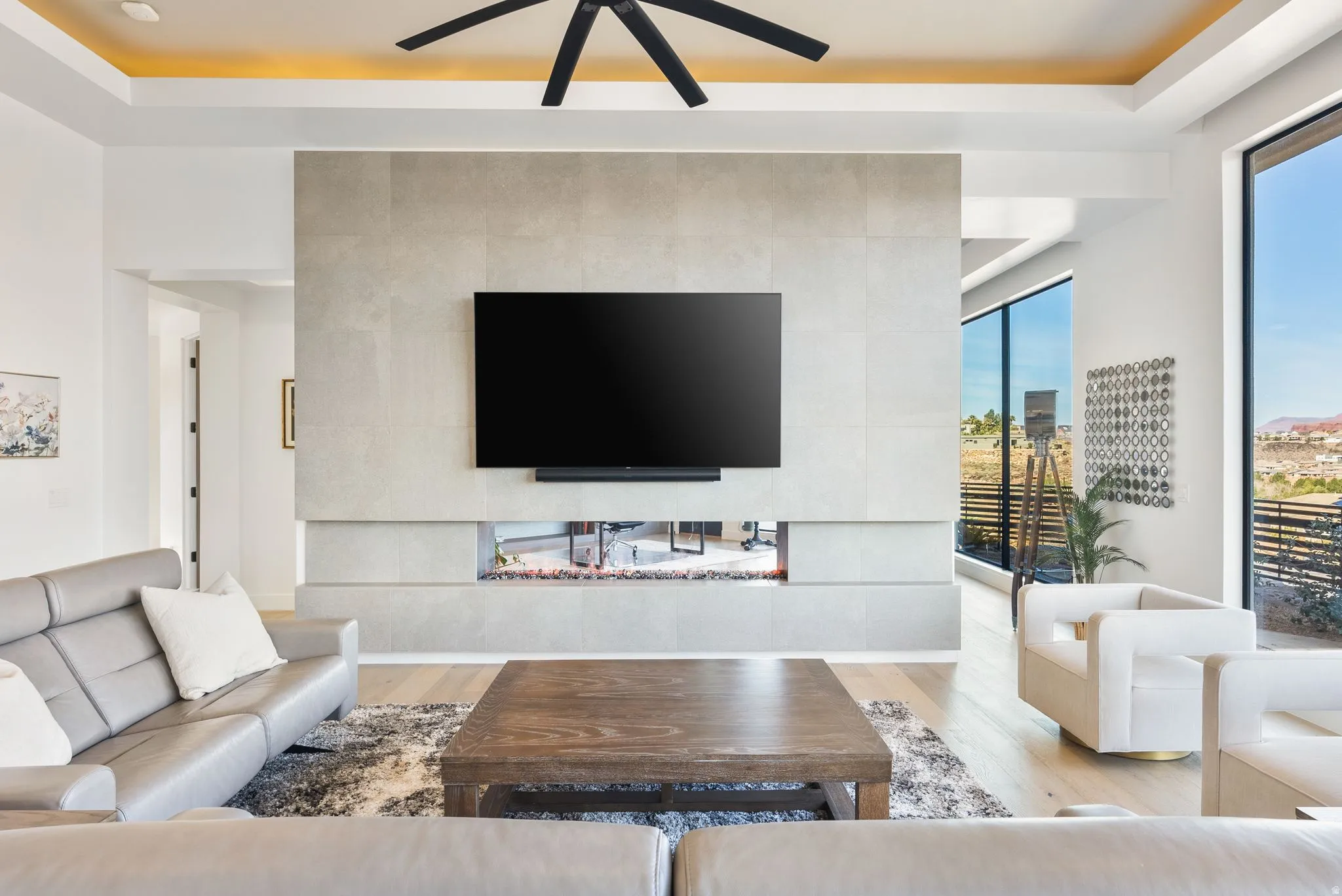 Living area featuring light wood-type flooring, ceiling fan, and a raised ceiling