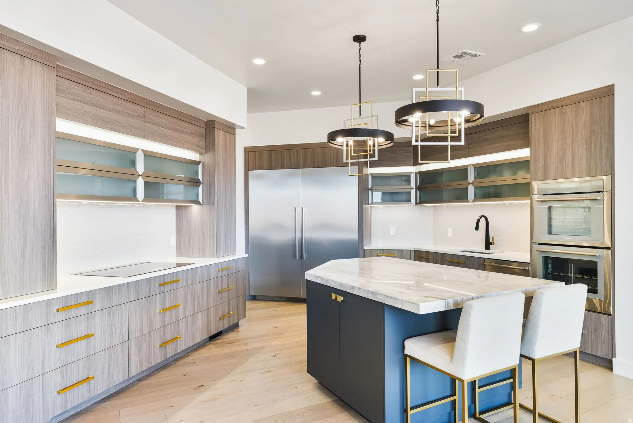 Kitchen featuring glass fronted cabinets, a center island, stainless steel appliances, a kitchen breakfast bar, and light wood finished floors