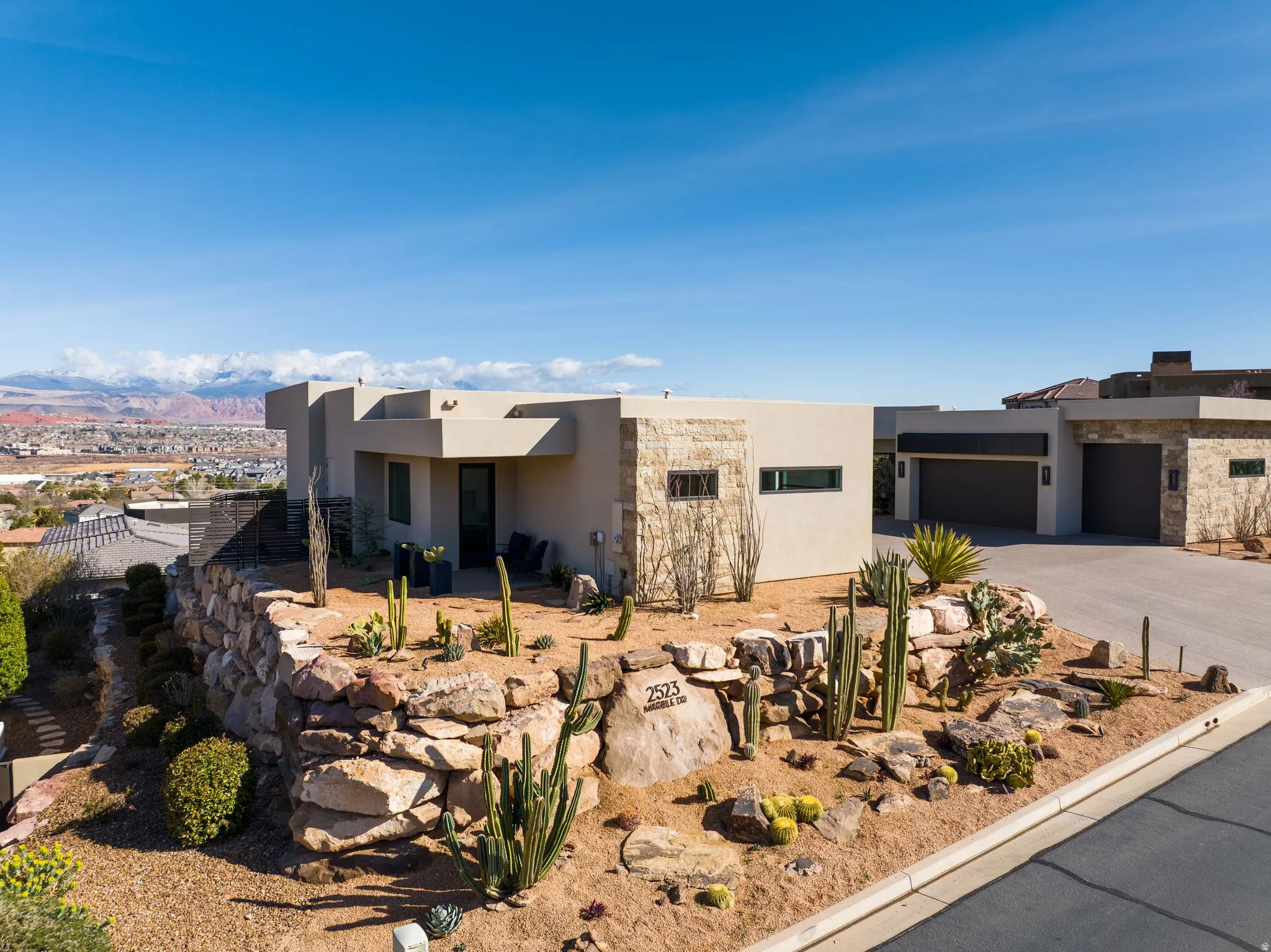 Southwest-style home with stucco siding, an attached garage, a mountain view, driveway, and a patio area