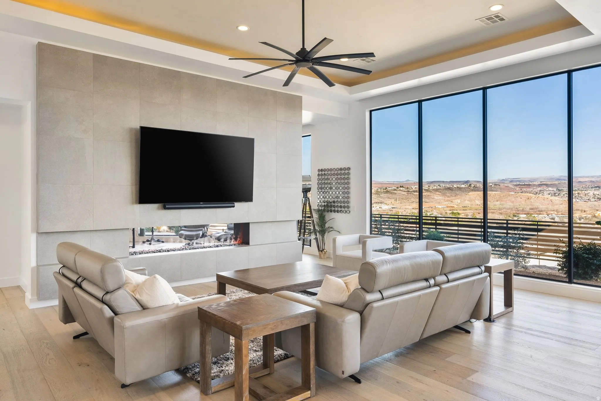 Living area with ceiling fan, light wood finished floors, a raised ceiling, a tiled fireplace, and recessed lighting