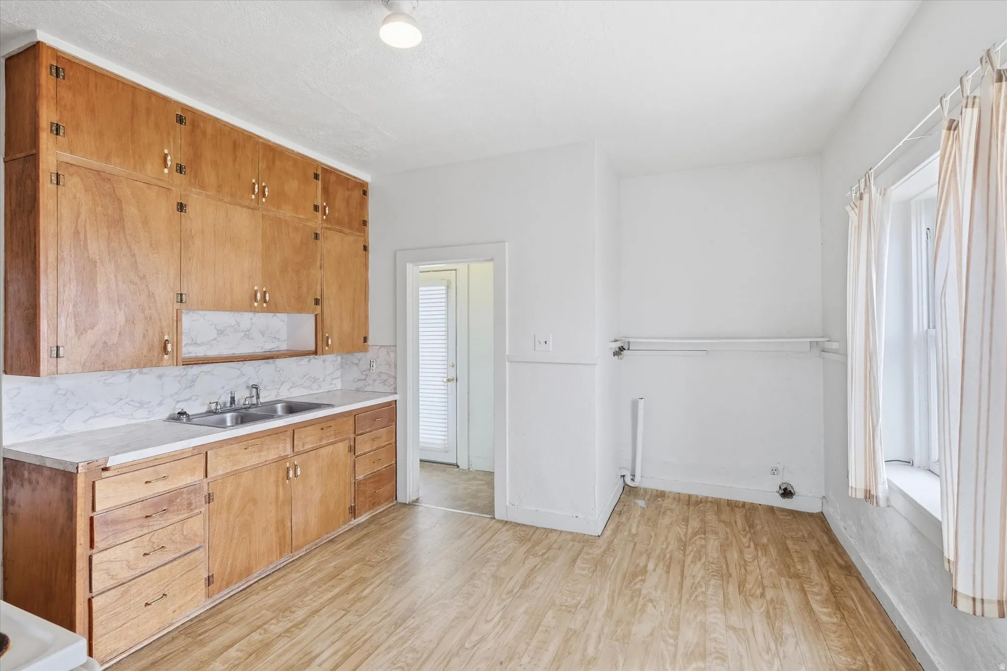 Kitchen featuring light countertops, light wood-style floors, tasteful backsplash, and wood finish cabinetry