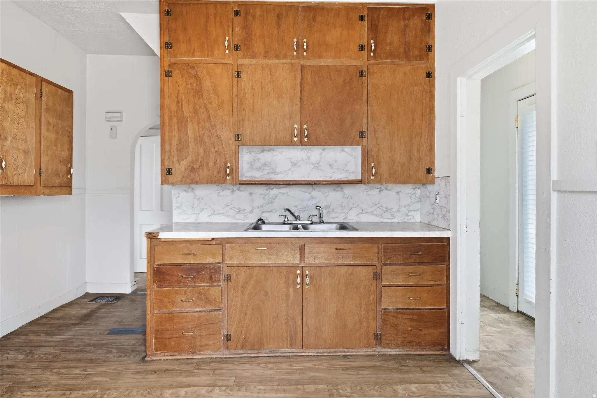 Kitchen with light countertops, wood finish cabinets, arched walkways, and light wood finished floors