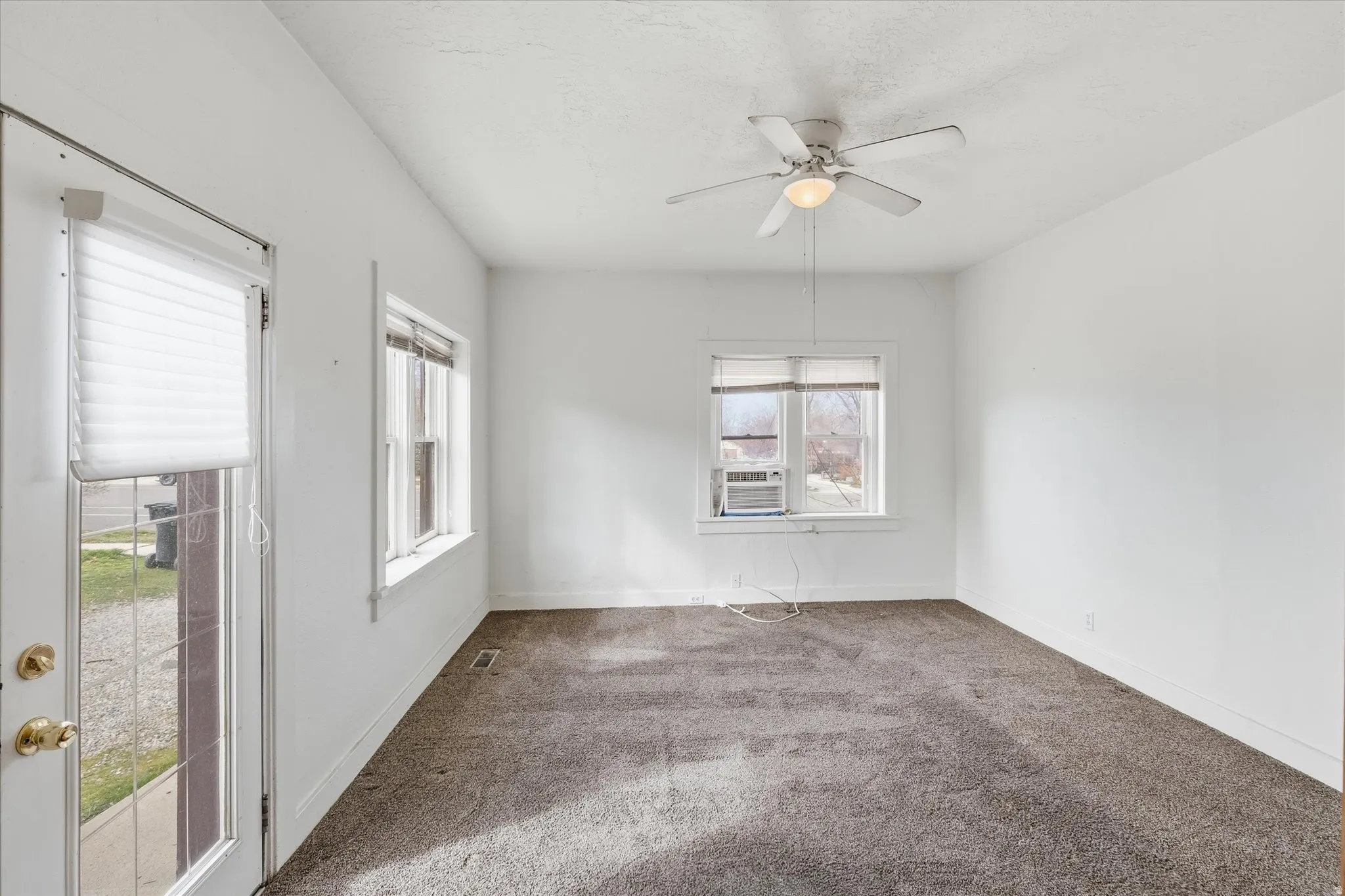 Empty room featuring carpet, ceiling fan, and cooling unit