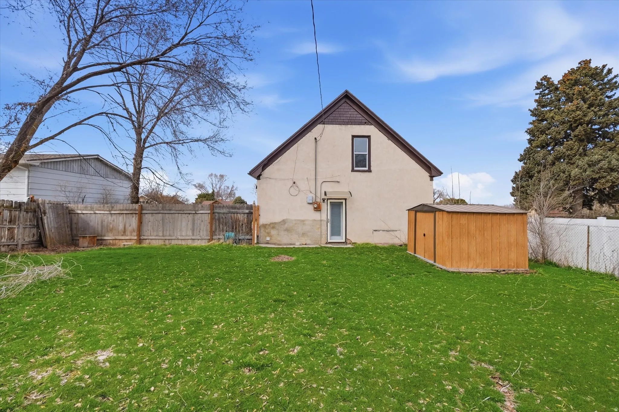 Back of house with a fenced backyard, stucco siding, and a storage shed