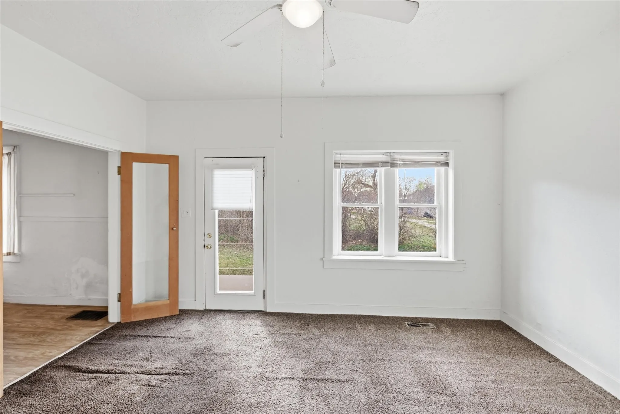 Carpeted empty room with plenty of natural light and a ceiling fan