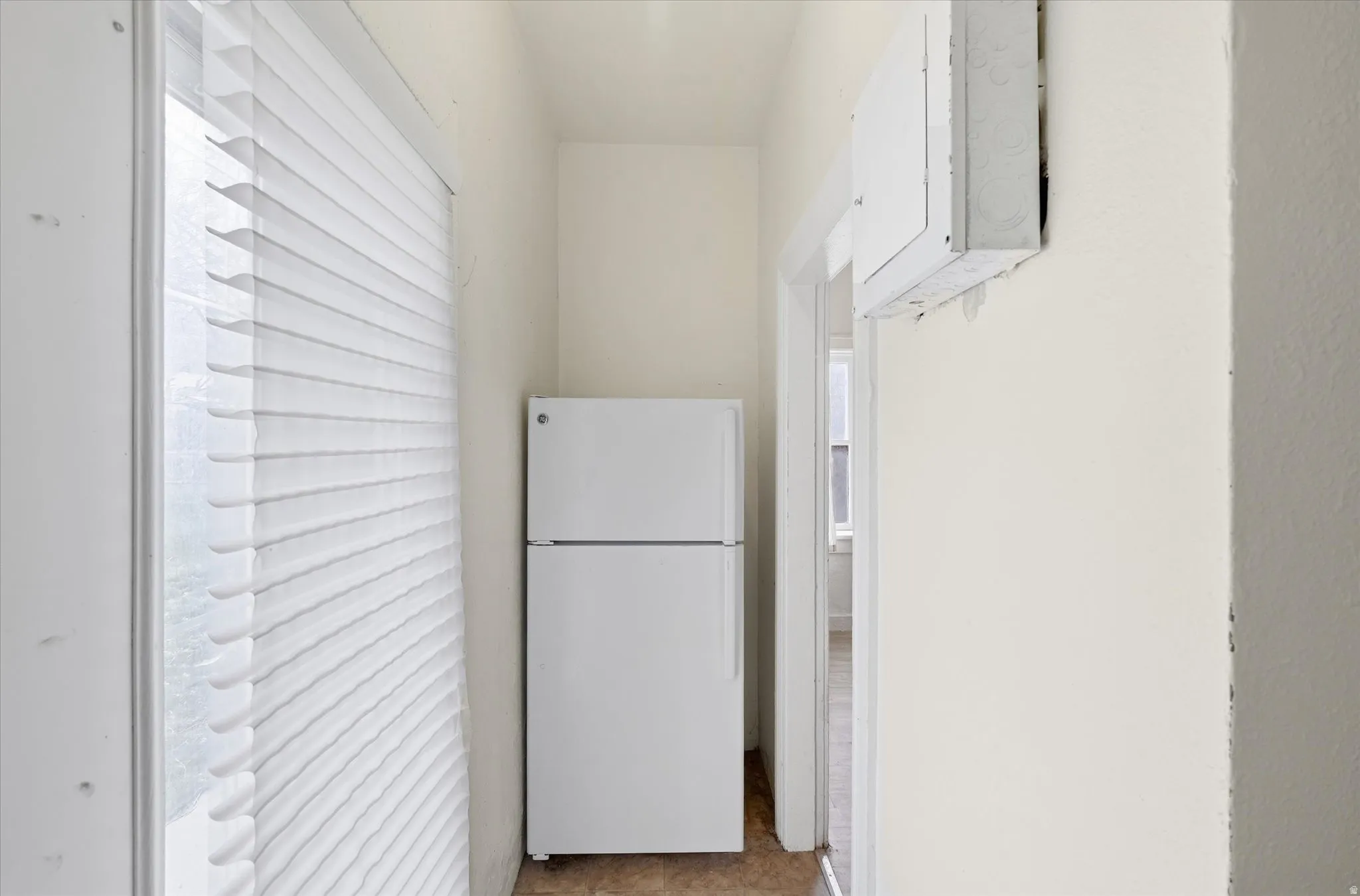 Kitchen with freestanding refrigerator, white cabinetry, and electric panel