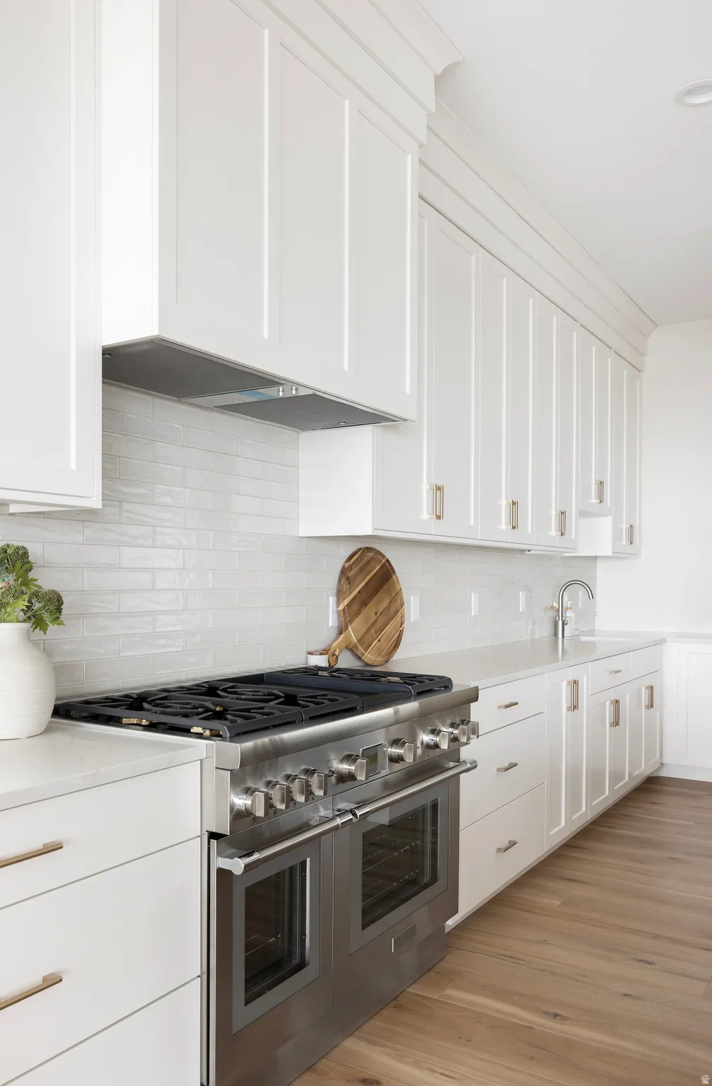 Kitchen featuring range with two ovens, white cabinetry, decorative backsplash, and light wood-style floors