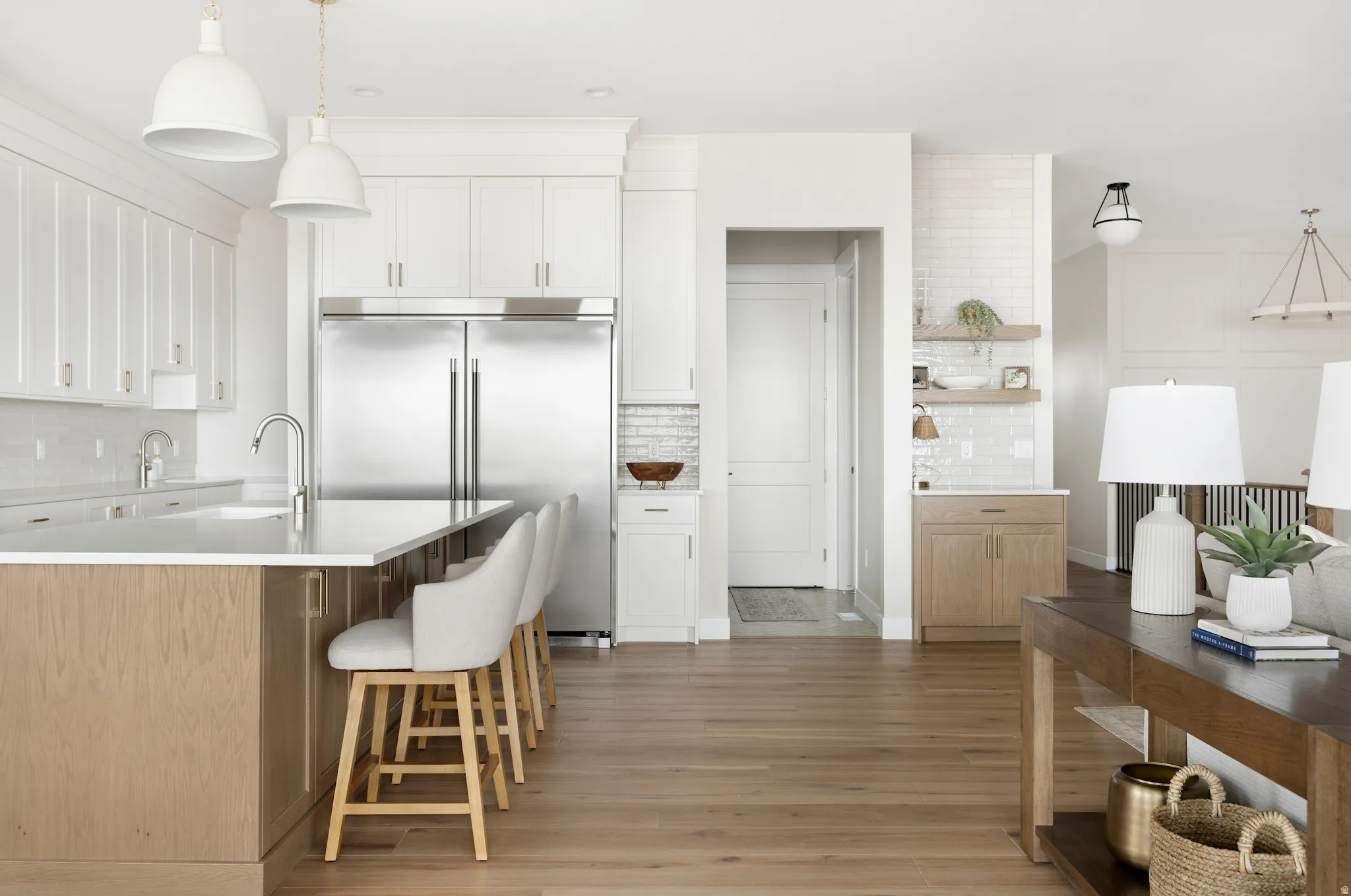 Kitchen featuring pendant lighting, tasteful backsplash, two tone cabinets, built in refrigerator, and a breakfast bar