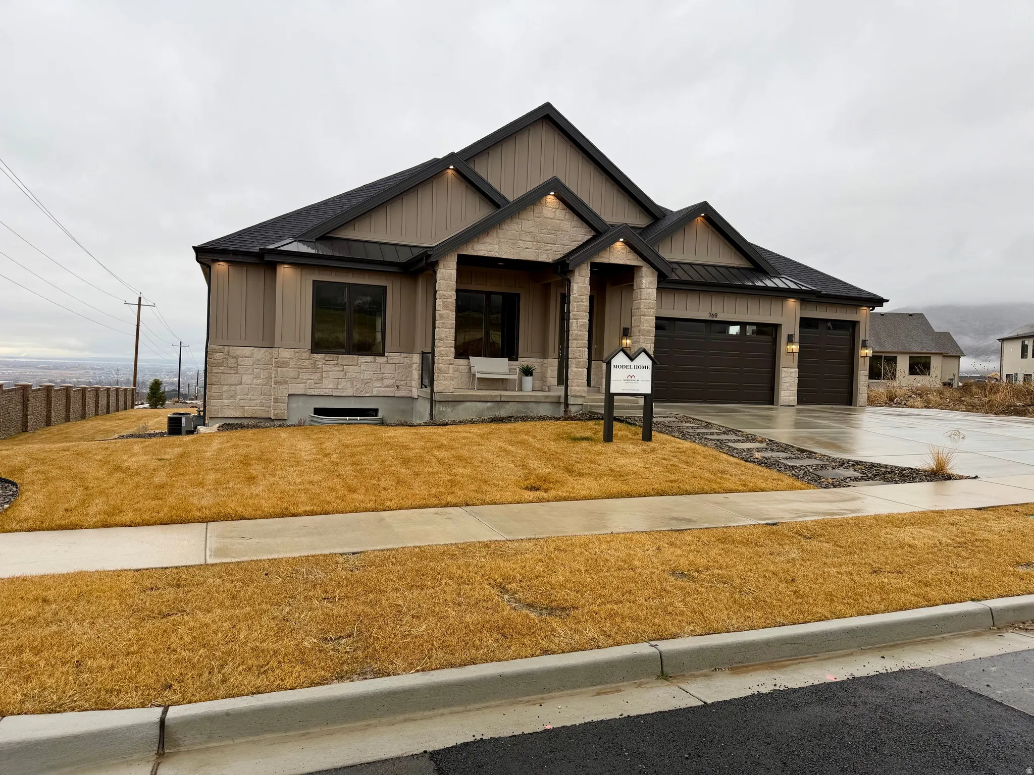 View of front of property featuring stone siding, a standing seam roof, a porch, concrete driveway, and an attached garage