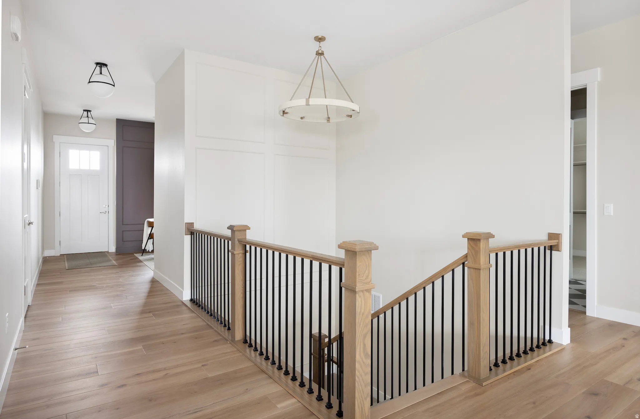 Hall with light wood-style floors and an upstairs landing