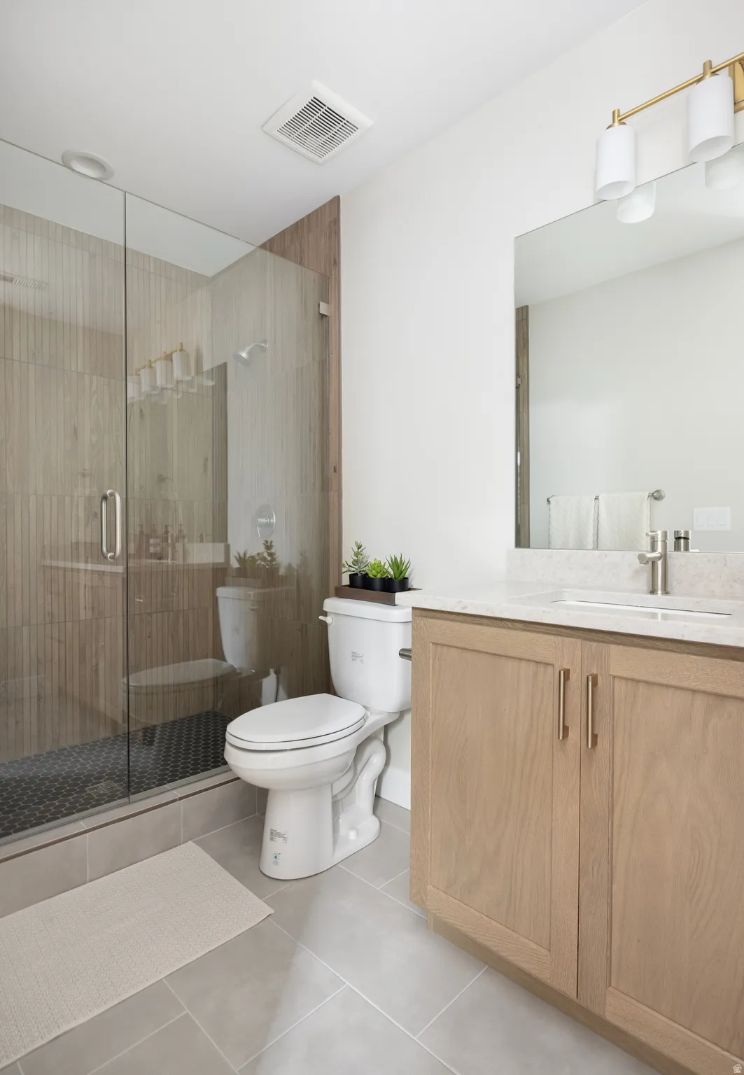 Full bath with vanity, a shower stall, and light tile patterned flooring