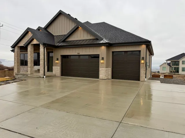 View of front of property featuring stone siding, board and batten siding, a shingled roof, and an attached garage