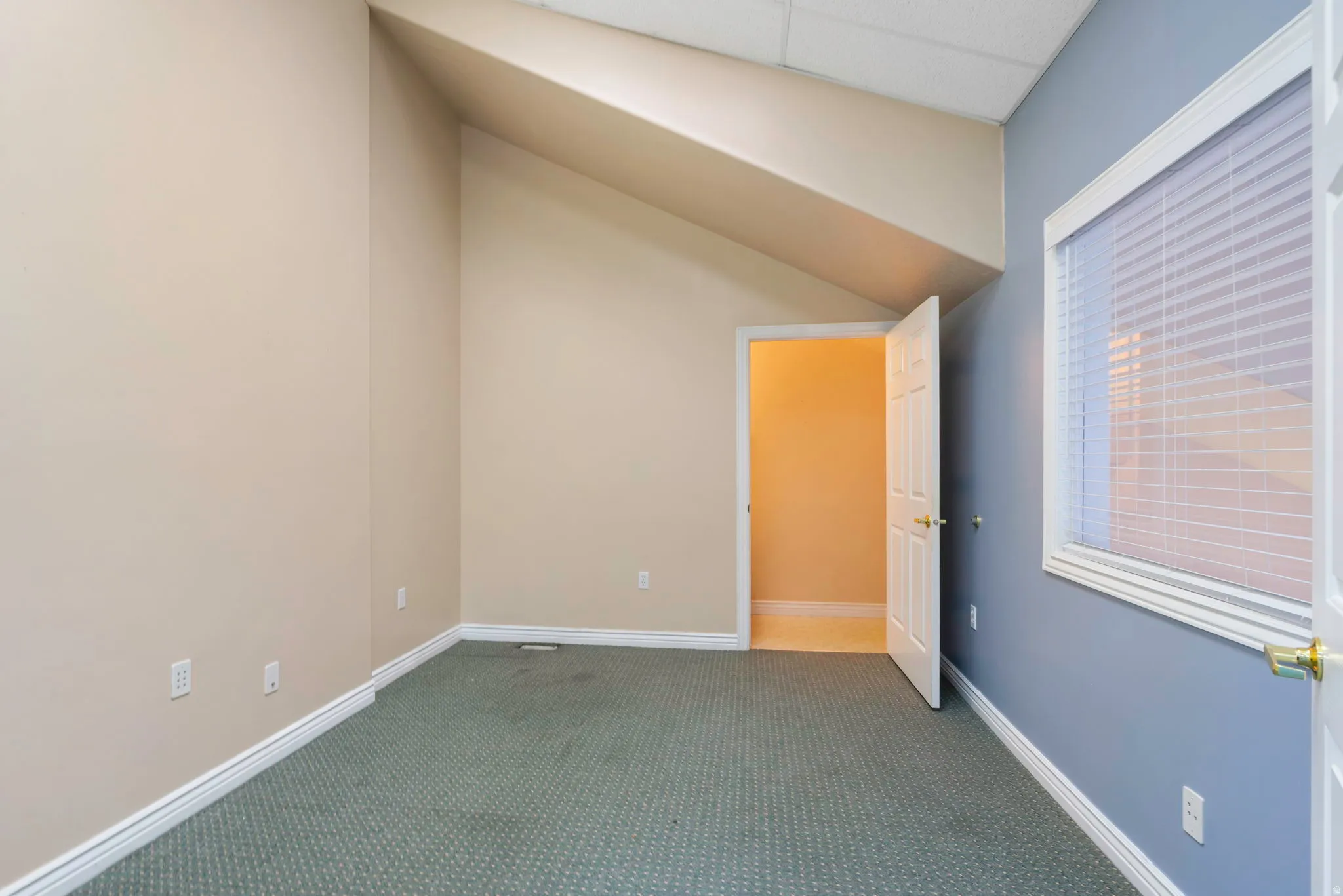 Unfurnished bedroom featuring dark colored carpet, lofted ceiling, and a drop ceiling