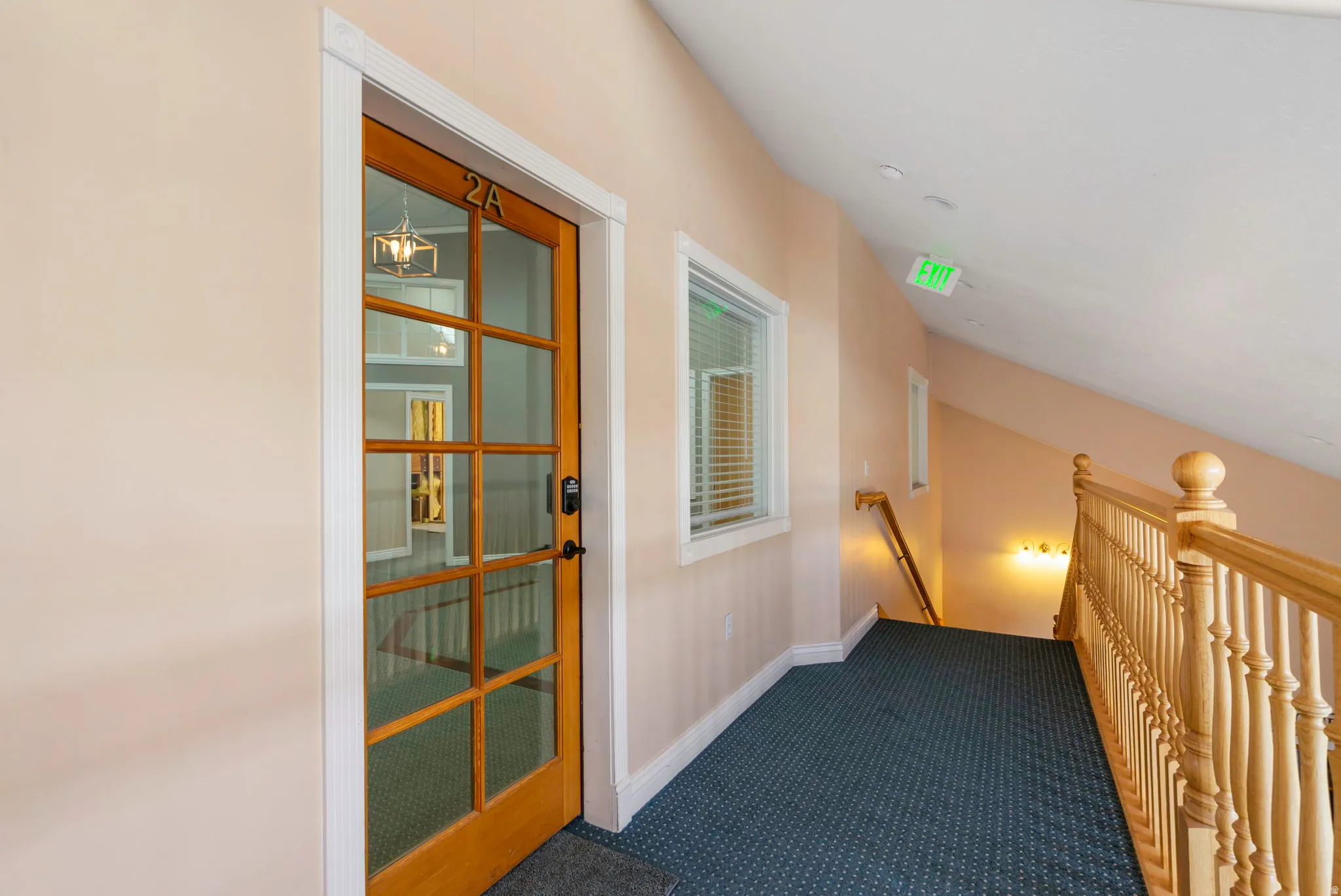 Hall with an upstairs landing and dark colored carpet