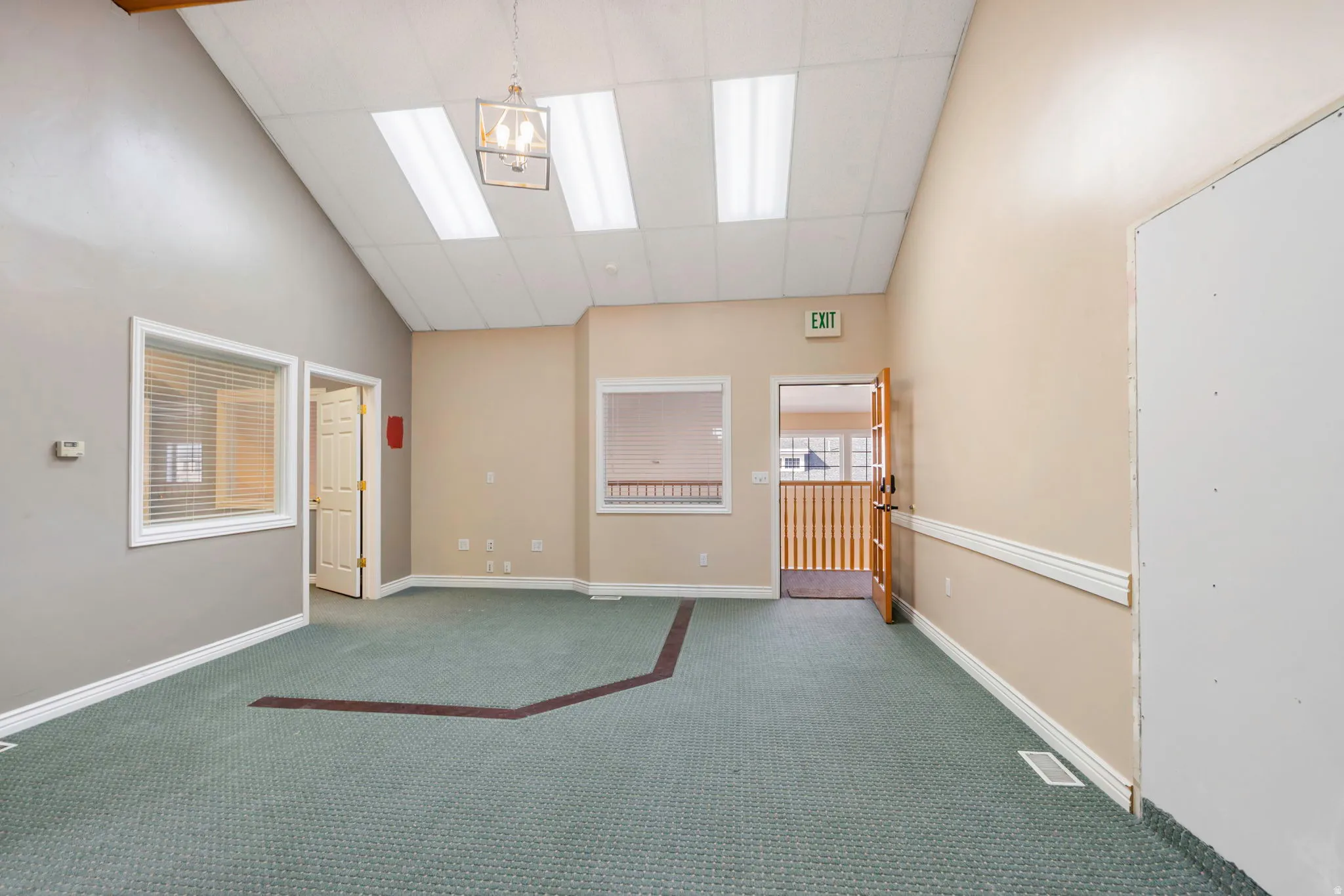 Carpeted spare room with a high drop ceiling and lofted ceiling
