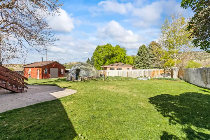 Expansive green lawn with a curved concrete patio and wooden deck stairs