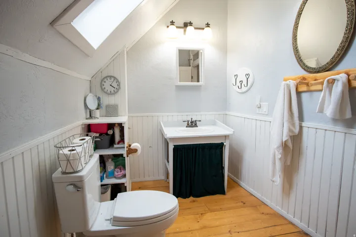 Bathroom featuring lofted ceiling, wainscoting, vanity, a textured wall, and a skylight