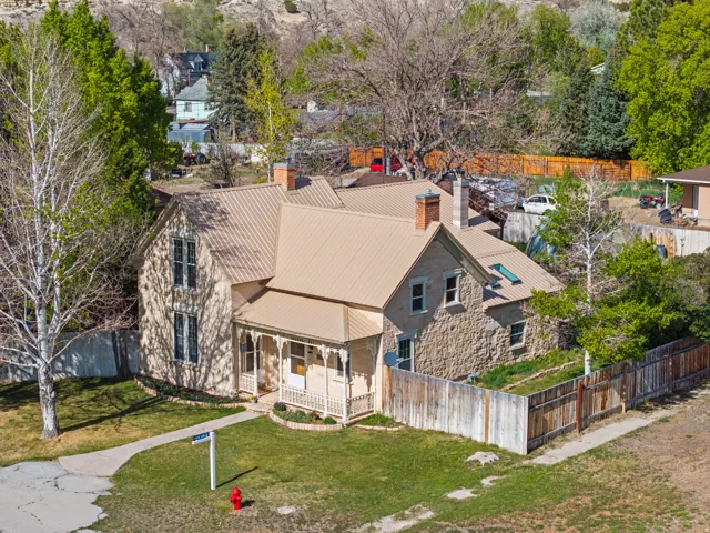 Stone and siding exterior with a covered porch, featuring a metal roof and two brick chimneys