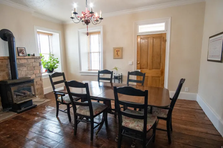 Dining room featuring a wood stove, dark wood finished floors, hanging lights, and crown molding