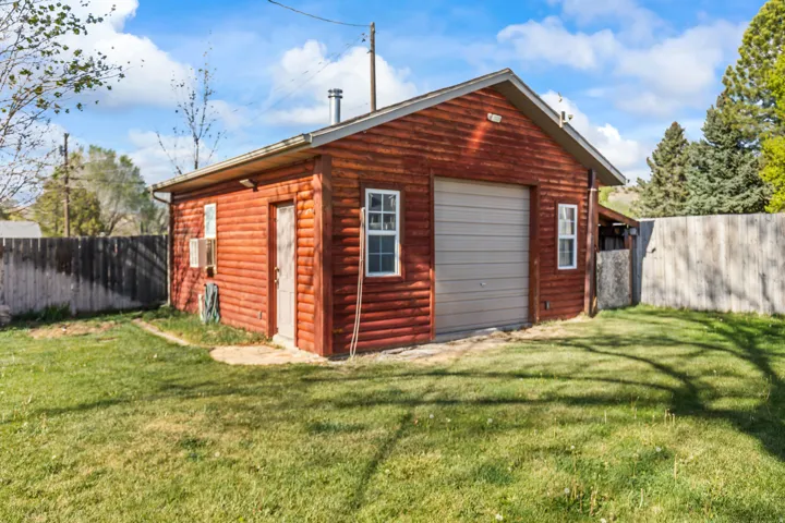 Detached garage with log-style siding, a single bay door, and an exterior side entry