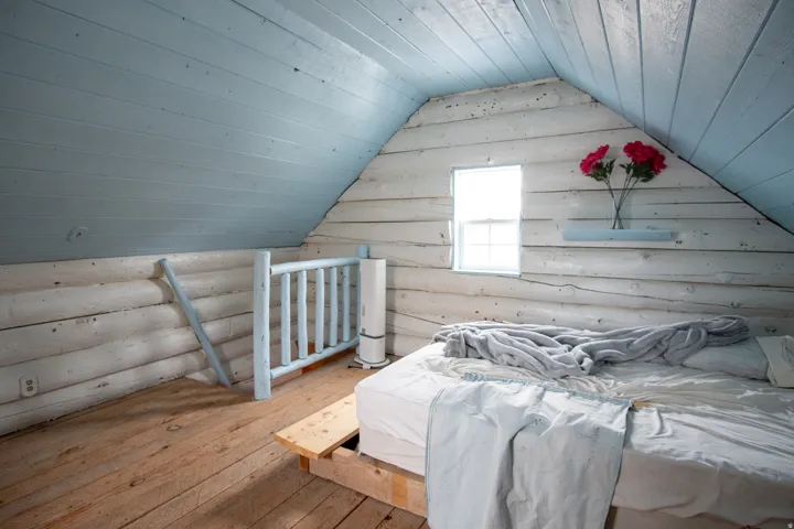 ADU loft bedroom featuring wood-type flooring and rustic walls