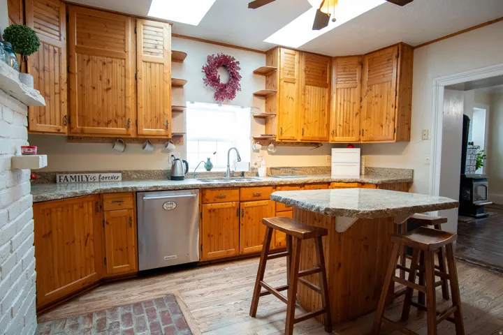 Kitchen with a kitchen bar, light wood-type flooring, dishwasher, ornamental molding, and a skylight