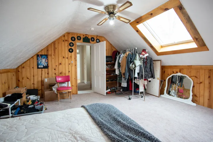 Bedroom featuring wood walls, a skylight, carpet flooring, and ceiling fan