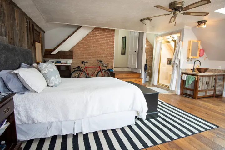 Master Bedroom with hardwood / wood-style flooring, a textured ceiling, a ceiling fan, wood walls, and connected bathroom