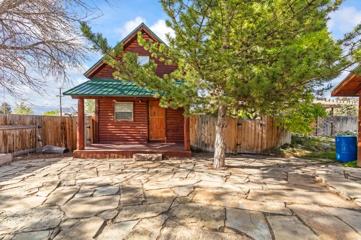 Log cabin exterior featuring a covered front porch, a green metal roof, and natural wood siding