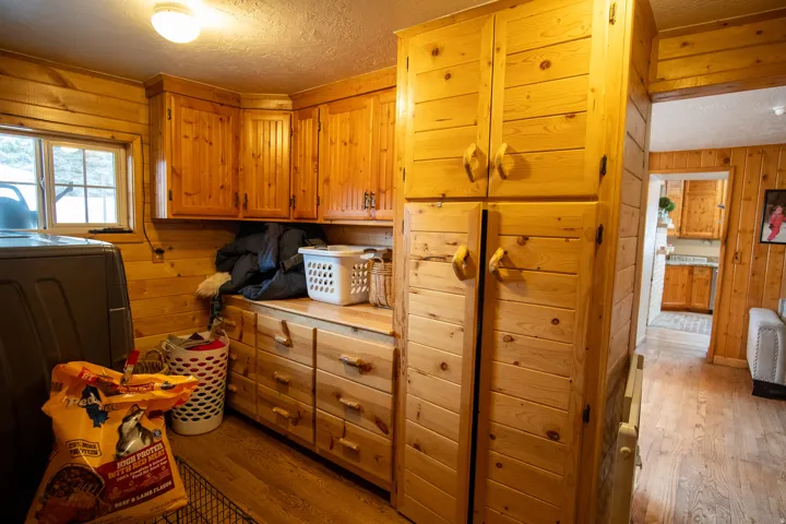 Laundry area with wooden walls, cabinet space, dark wood-style floors, and washing machine and dryer