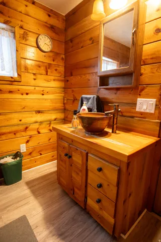 Bathroom with vanity, light wood-style floors, and wood walls