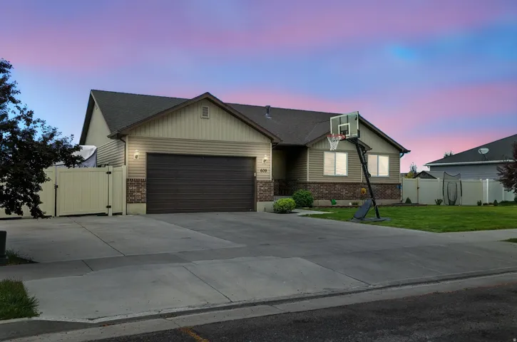 View of front of house with a gate, brick siding, an attached garage, and concrete driveway
