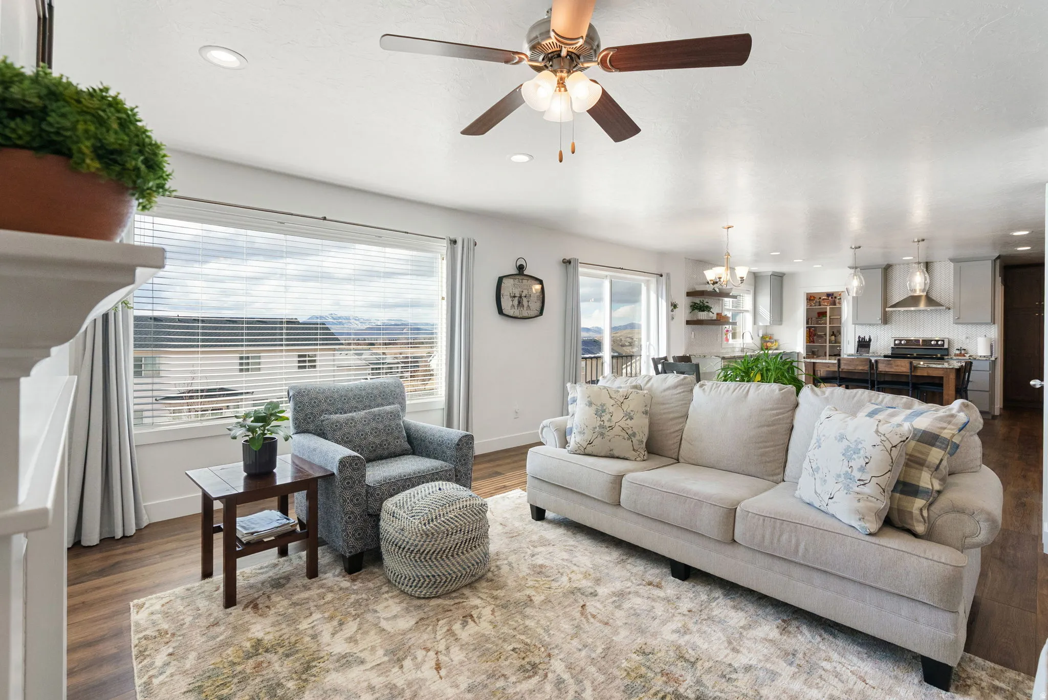Living area featuring dark wood-style floors, suspended lighting, and ceiling fan