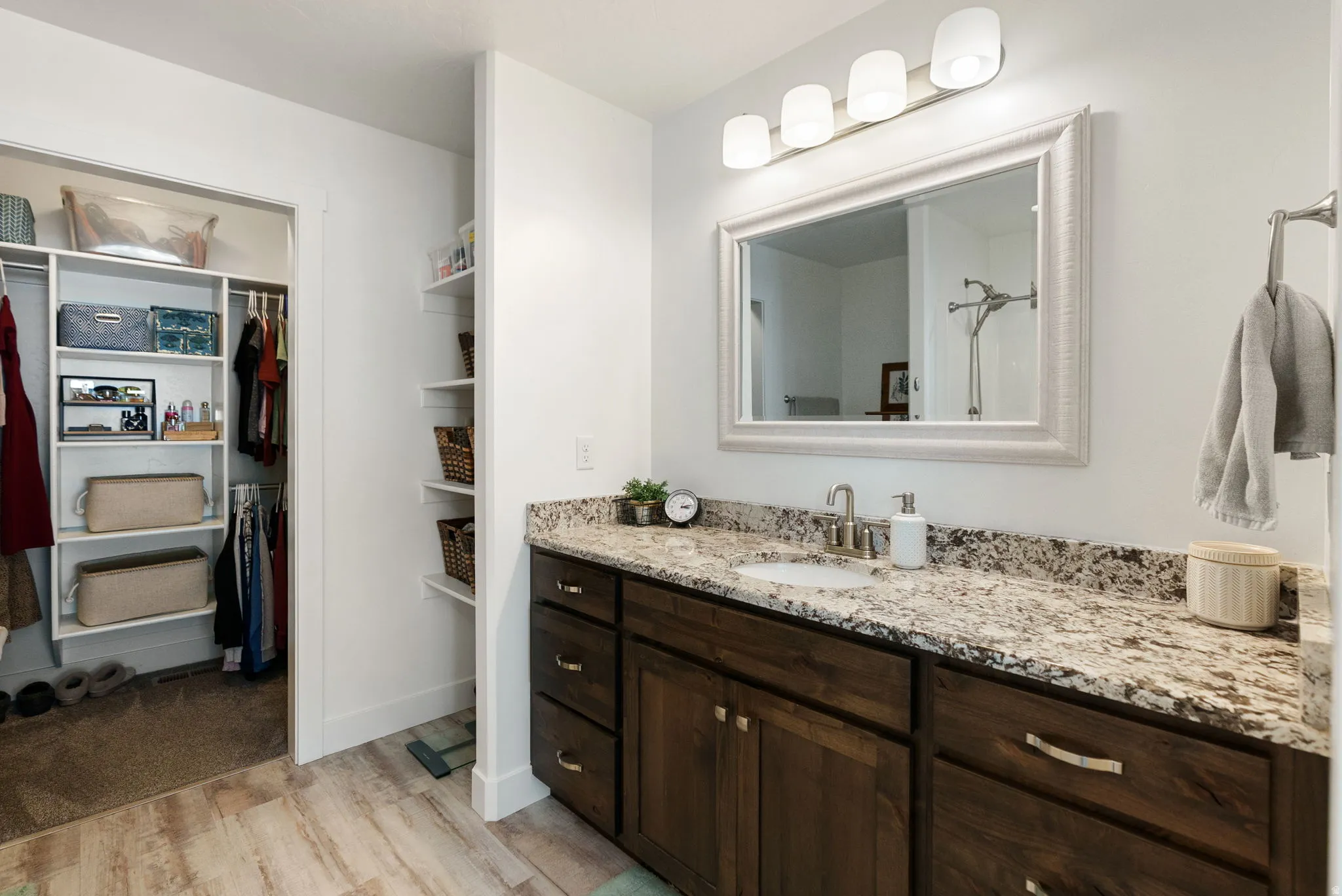 Bathroom featuring vanity, light wood-style flooring, a shower, and a walk in closet