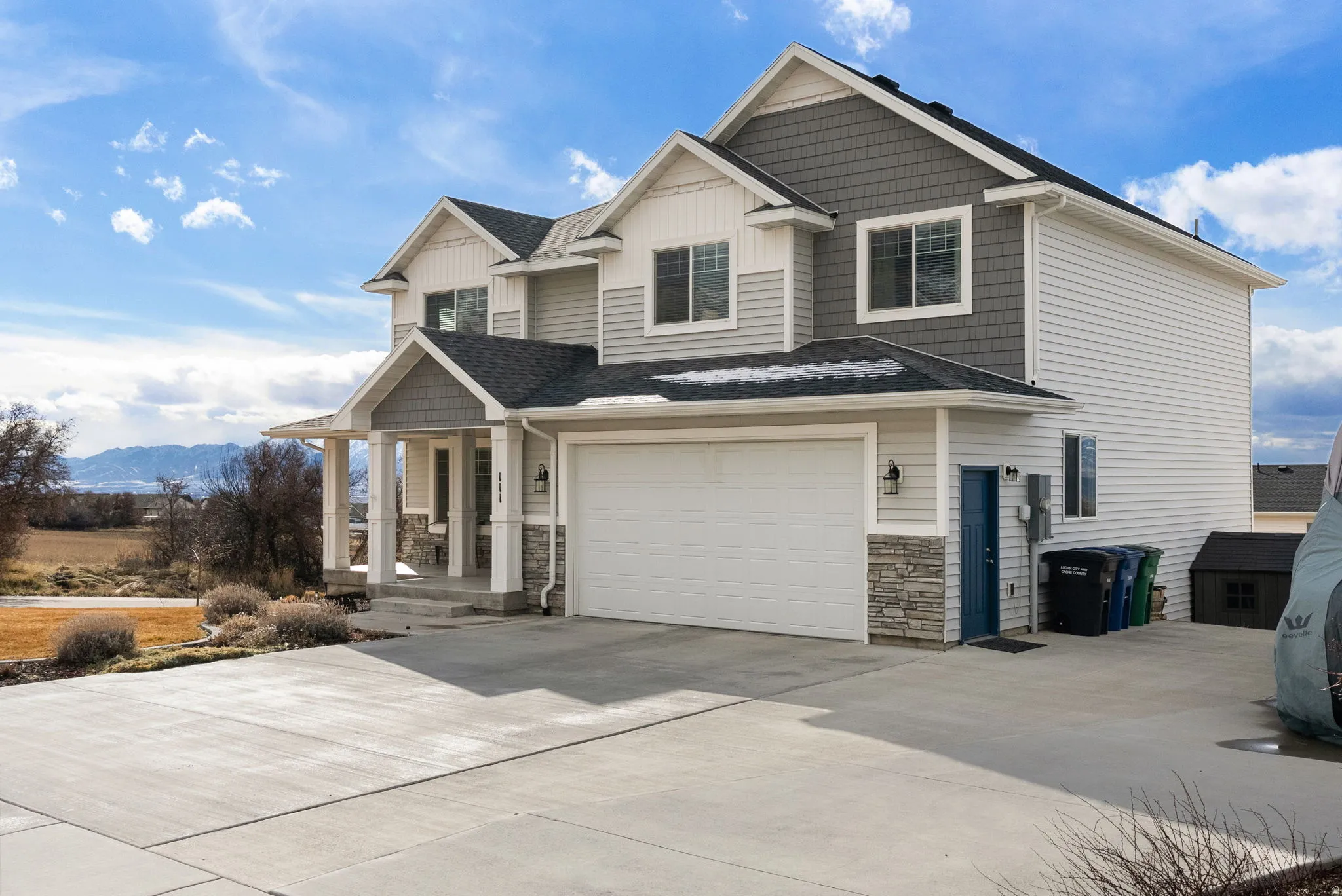 Craftsman house featuring a porch, roof with shingles, concrete driveway, an attached garage, and stone siding