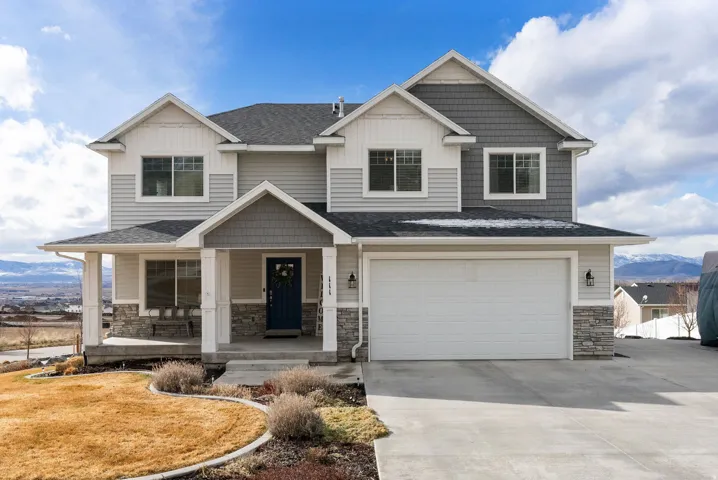 Craftsman-style home with a mountain view, stone siding, covered porch, a garage, and roof with shingles
