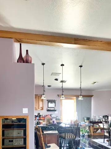 Dining space with a textured ceiling, beamed ceiling, and wine cooler