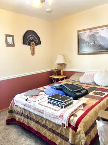 Carpeted bedroom featuring ceiling fan and baseboards