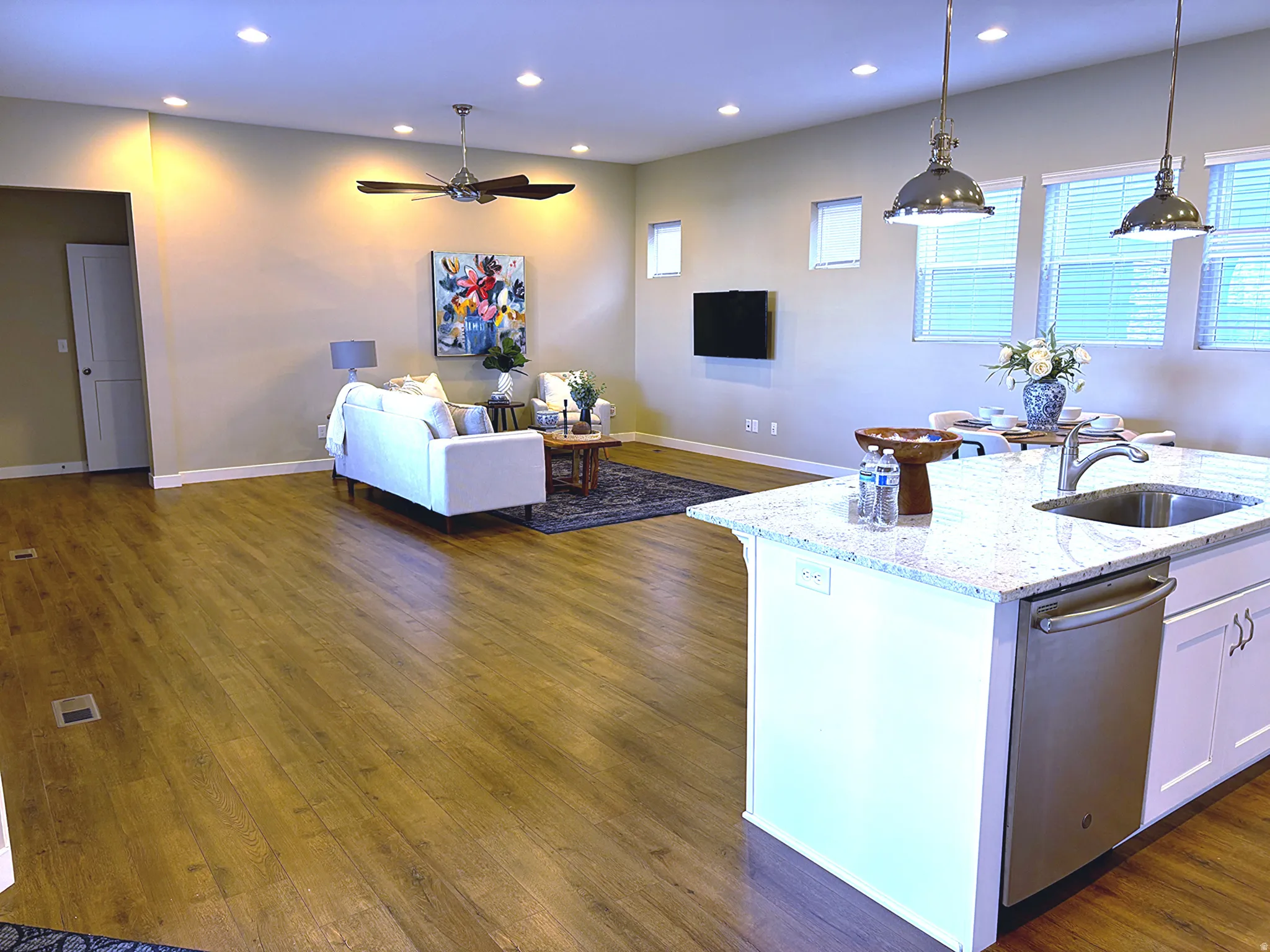 Kitchen with light stone countertops, open floor plan, dark wood finished floors, and a center island with sink