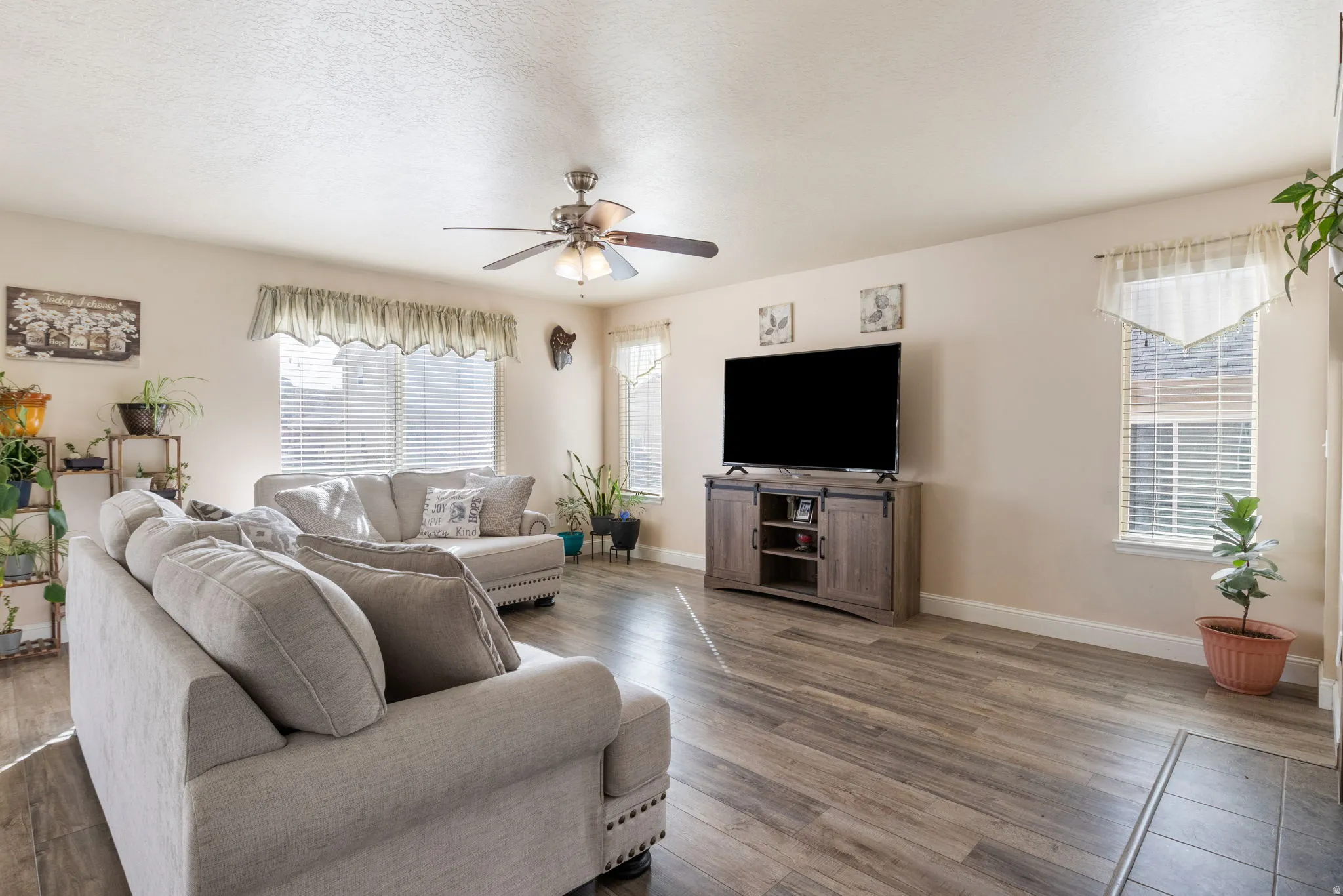 Living room featuring a ceiling fan, wood finished floors, and plenty of natural light