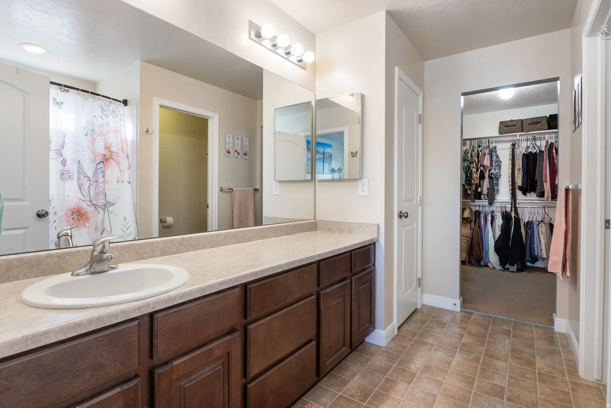 Master-Full bathroom featuring vanity, curtained shower, a walk in closet, and a textured ceiling