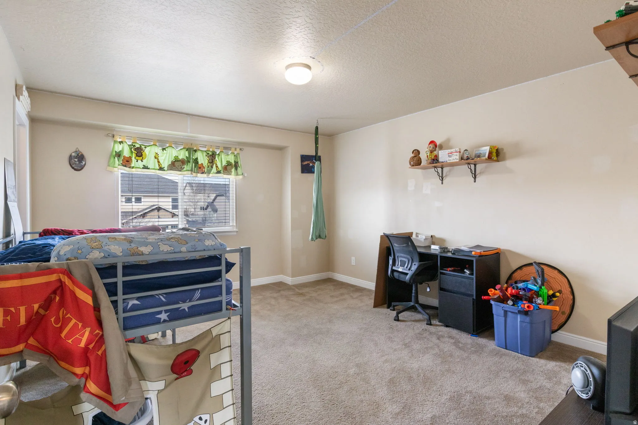 Bedroom featuring light carpet, a textured ceiling, and a desk