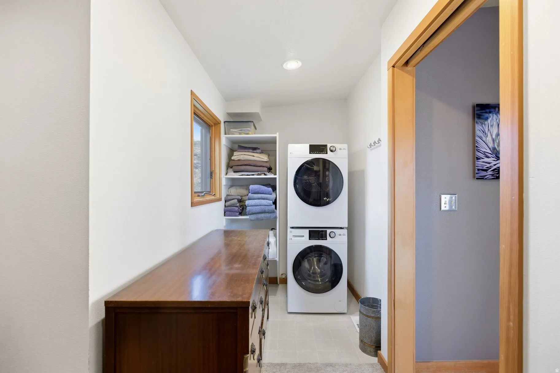 Laundry room featuring stacked washer / drying machine and light flooring
