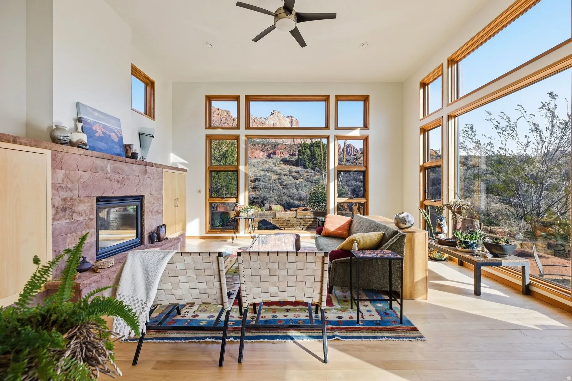 Living room with a tile fireplace, wood finished floors, a ceiling fan, a high ceiling, and healthy amount of natural light